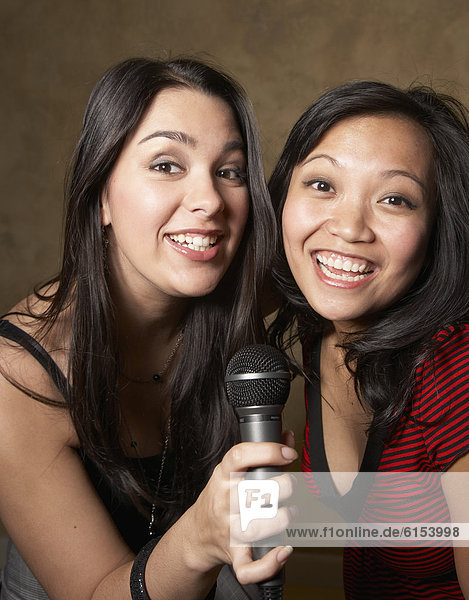 Multi-ethnic friends singing with microphone