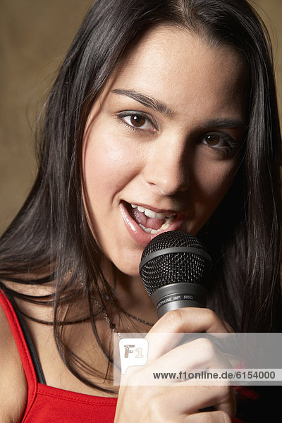 Hispanic woman singing with microphone