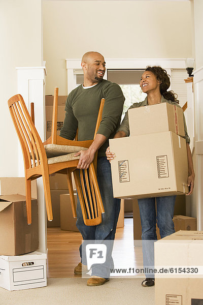 African couple moving boxes in new house