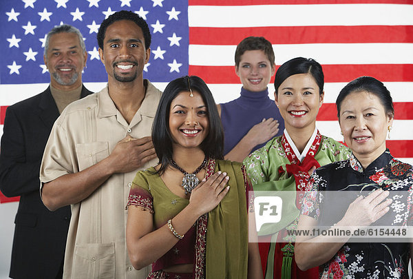 Multi-ethnic people standing in front of American flag