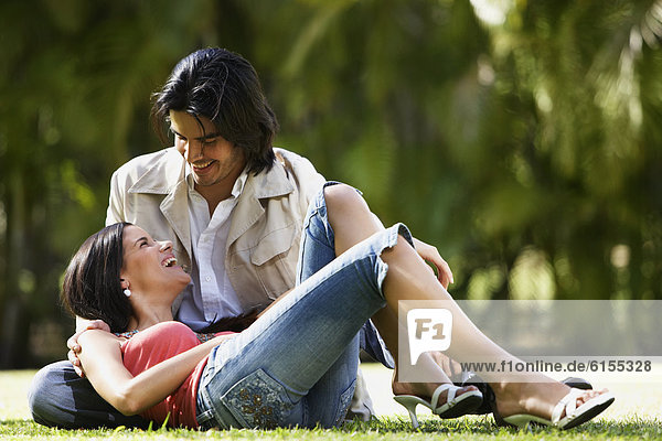 South American couple sitting on grass