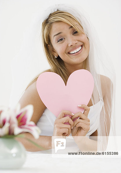 Hispanic bride holding paper cutout heart