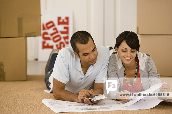 Young couple looking at blueprints in new house
