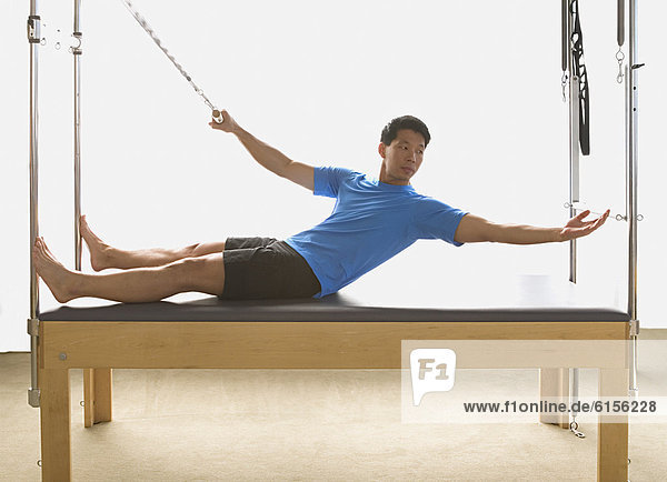 Asian man stretching on exercise equipment