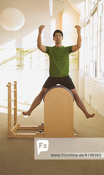 Asian man sitting in exercise equipment