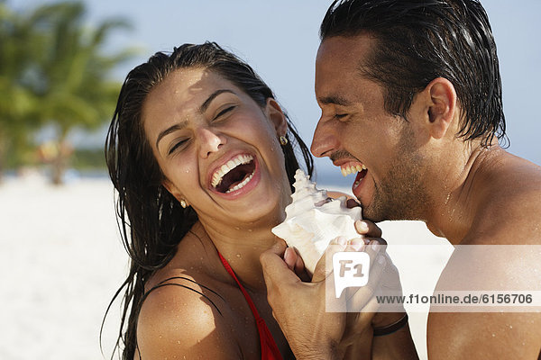 South American couple laughing at beach