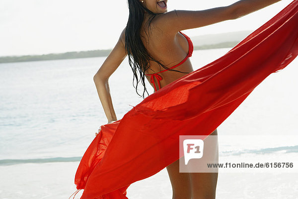 South American woman holding sarong at beach