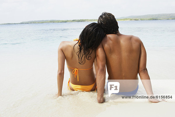 South American couple sitting on beach