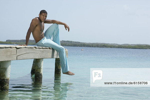 Hispanic man sitting on dock
