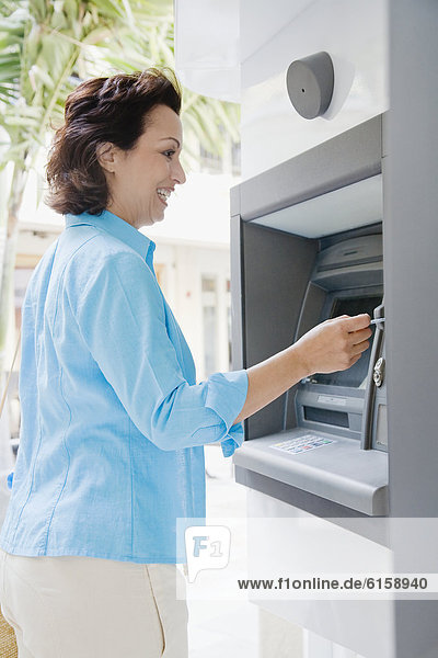 Hispanische Frau mit Geldautomaten