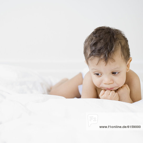 Hispanic baby laying on bed