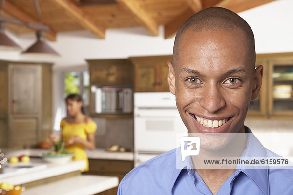 African man smiling with wife in background