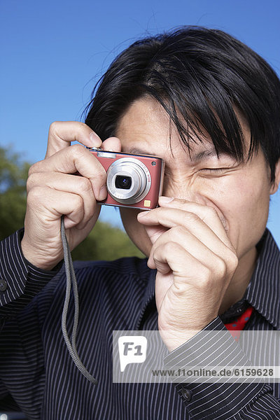 Asian man taking photograph