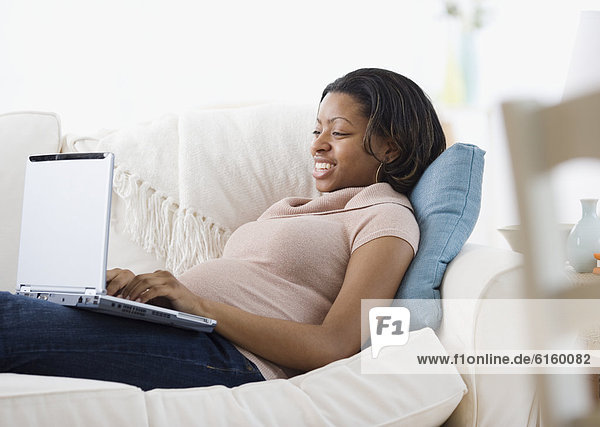 Pregnant African American woman typing on laptop
