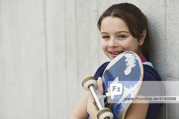 Mixed Race girl holding skateboard