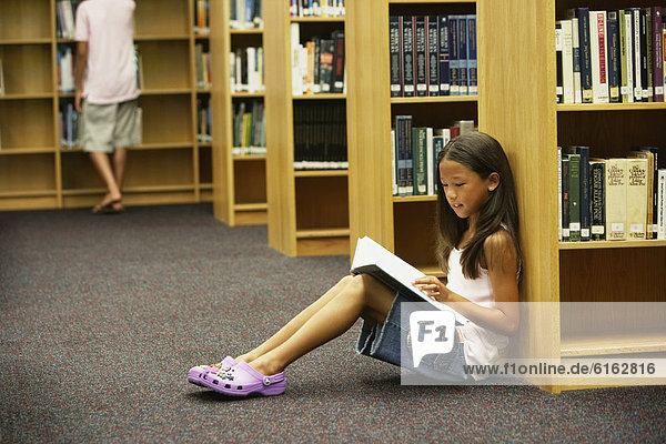 Asian girl reading library book
