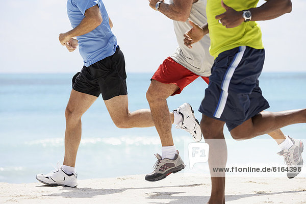Multi-ethnic men running in beach