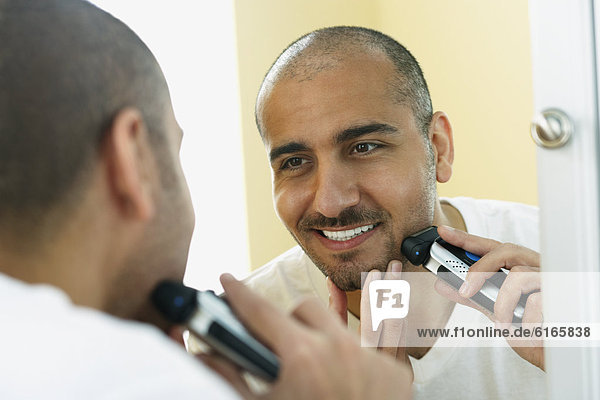 Middle Eastern man shaving with electric razor