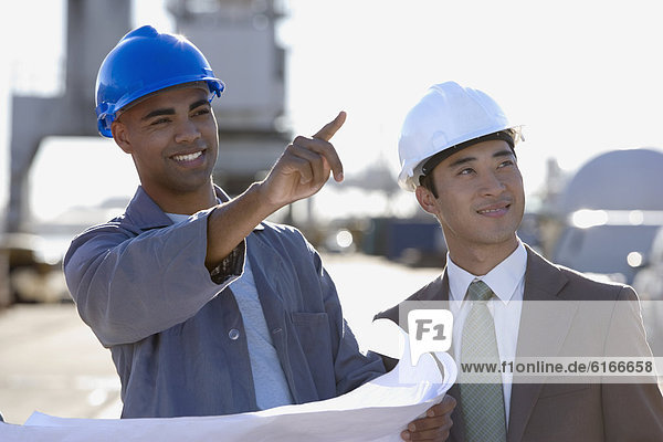 Multi-ethnic businessman and construction worker pointing