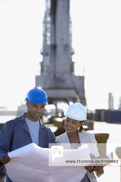 African American businesswoman and construction worker with blueprints