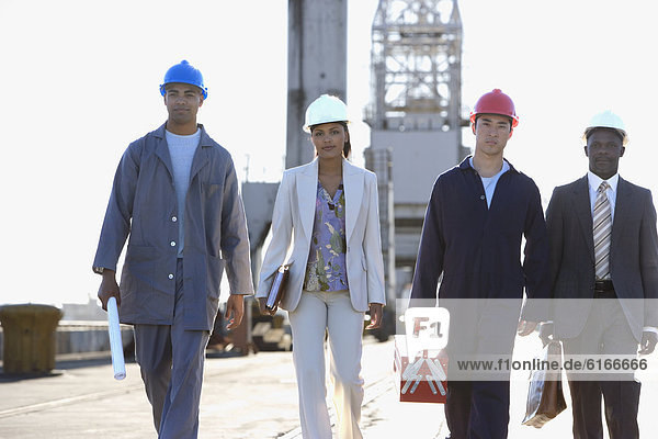 Multi-ethnic businesspeople and construction workers walking