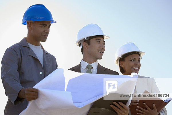 Multi-ethnic businesspeople and construction worker with blueprints