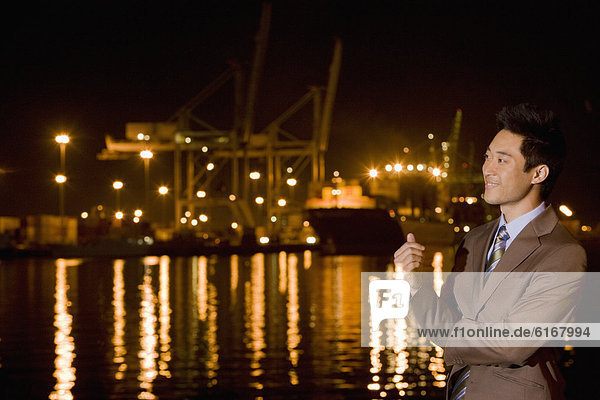 Asian businessman next to water at night