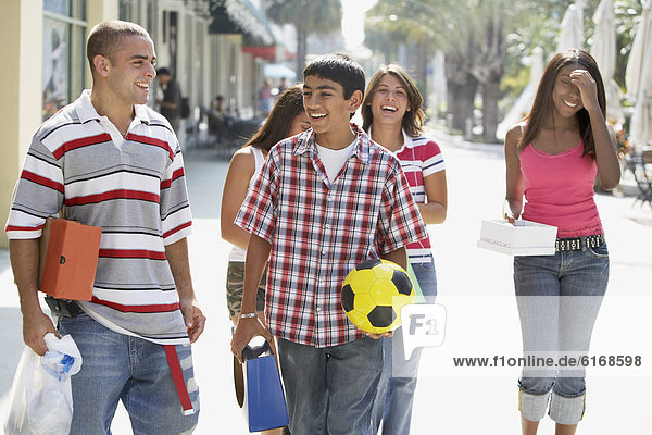 Multi-ethnic teenagers walking on sidewalk