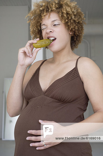 Pregnant African woman eating pickle