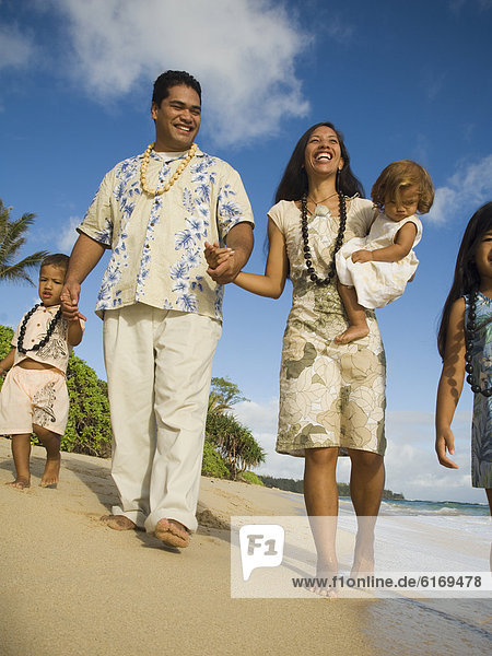 Pacific Islander family walking on beach