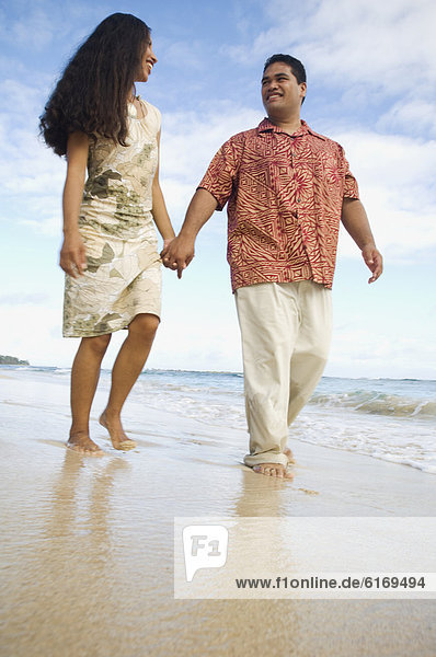 Pacific Islander couple walking on beach