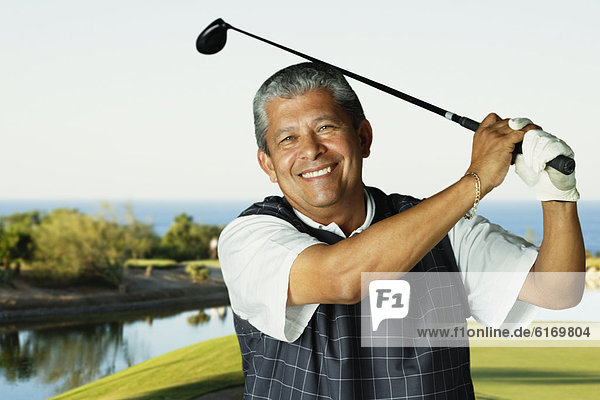 Hispanic man swinging golf club