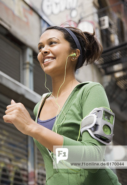 Mixed Race woman wearing headphones and jogging
