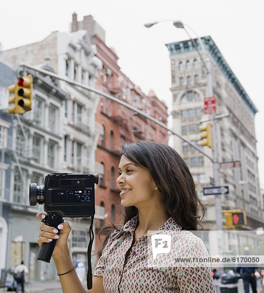 Mixed Race woman holding video camera