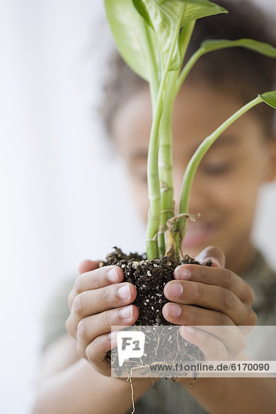 Mixed Race girl holding plant