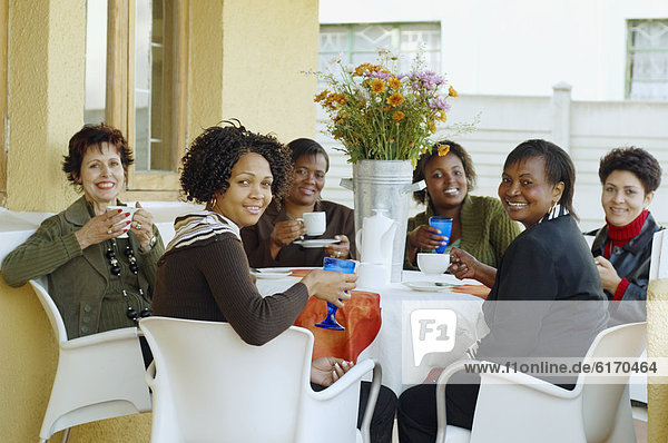 Multi-ethnic women having coffee outdoors