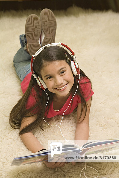 Pacific Islander girl listening to headphones and reading