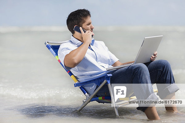 Hispanic man in beach chair with laptop