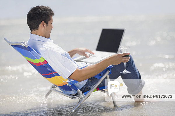 Hispanic man in beach chair with laptop