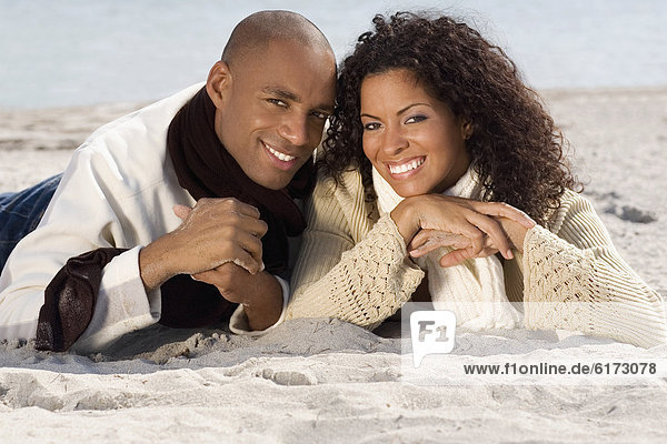 Multi-ethnic couple laying on beach
