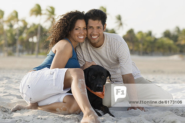 Hispanic couple and dog on beach