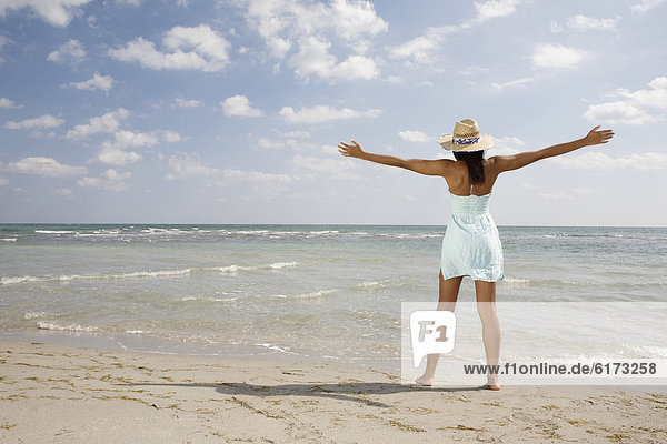 African woman with arms outstretched at beach