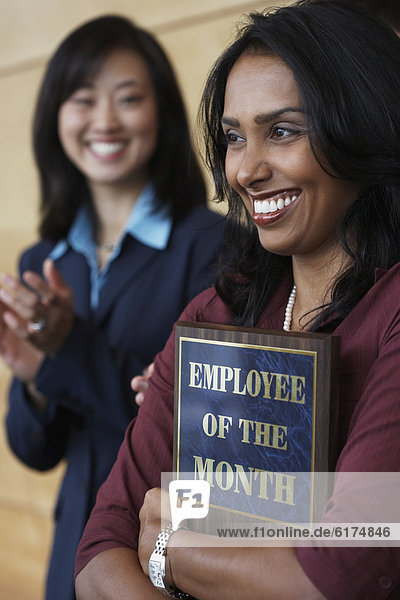 Businesswoman holding Employee of the Month plaque