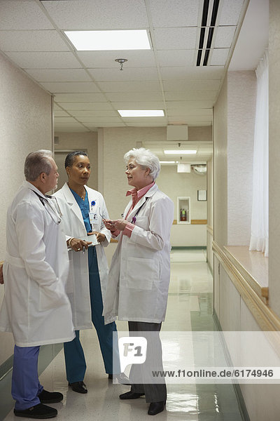 Three doctors talking in hospital hallway