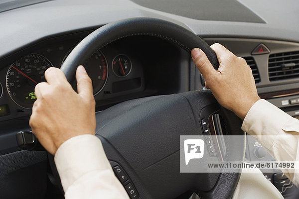 Close up of man's hands on steering wheel
