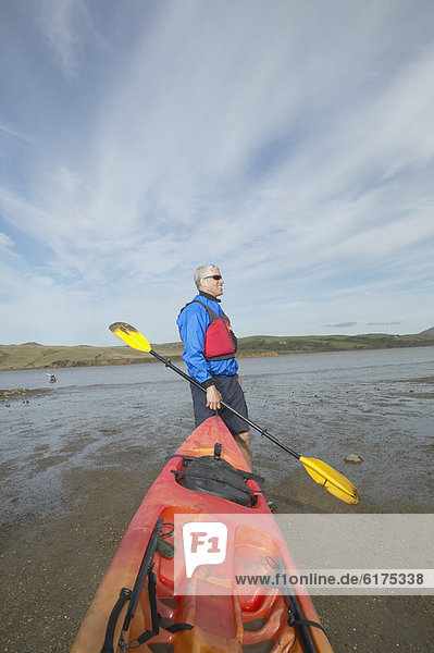 Middle-aged man holding kayak and paddle