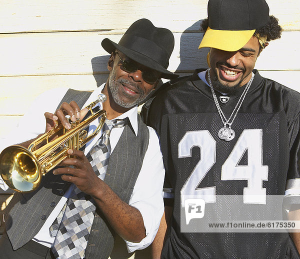 Young African man laughing next to senior African man with trumpet
