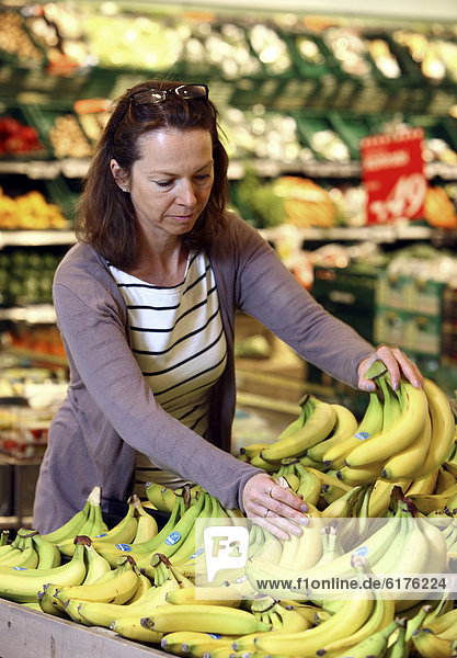 Obstabteilung  Frau kauft Bananen ein  Selbstbedienung  Lebensmittelabteilung  Supermarkt  Deutschland  Europa