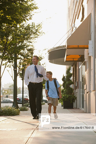 Caucasian businessman and son walking on city sidewalk