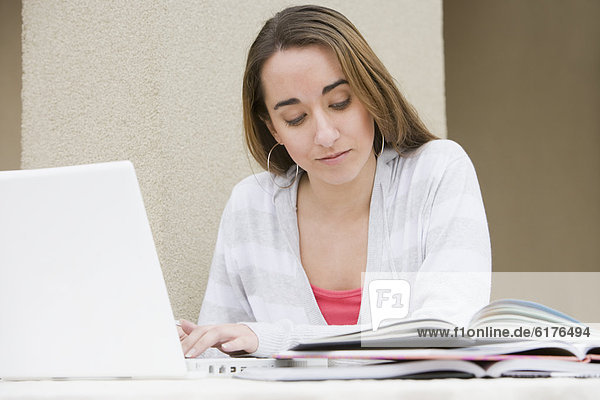 Hispanic woman using laptop for homework